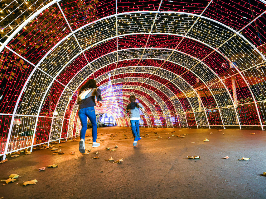 Two kids run through a tunnel of lights