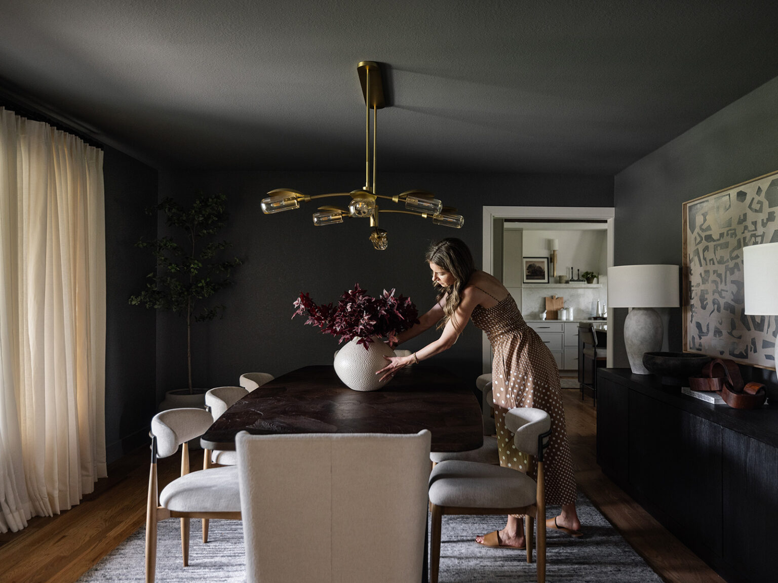 Woman adjusts a vase on a dining room table