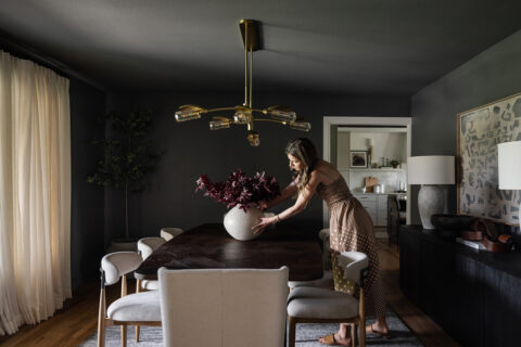 Woman adjusts a vase on a dining room table