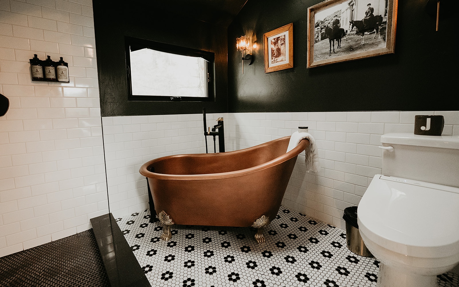 A copper soaking tub on black and white penny tile