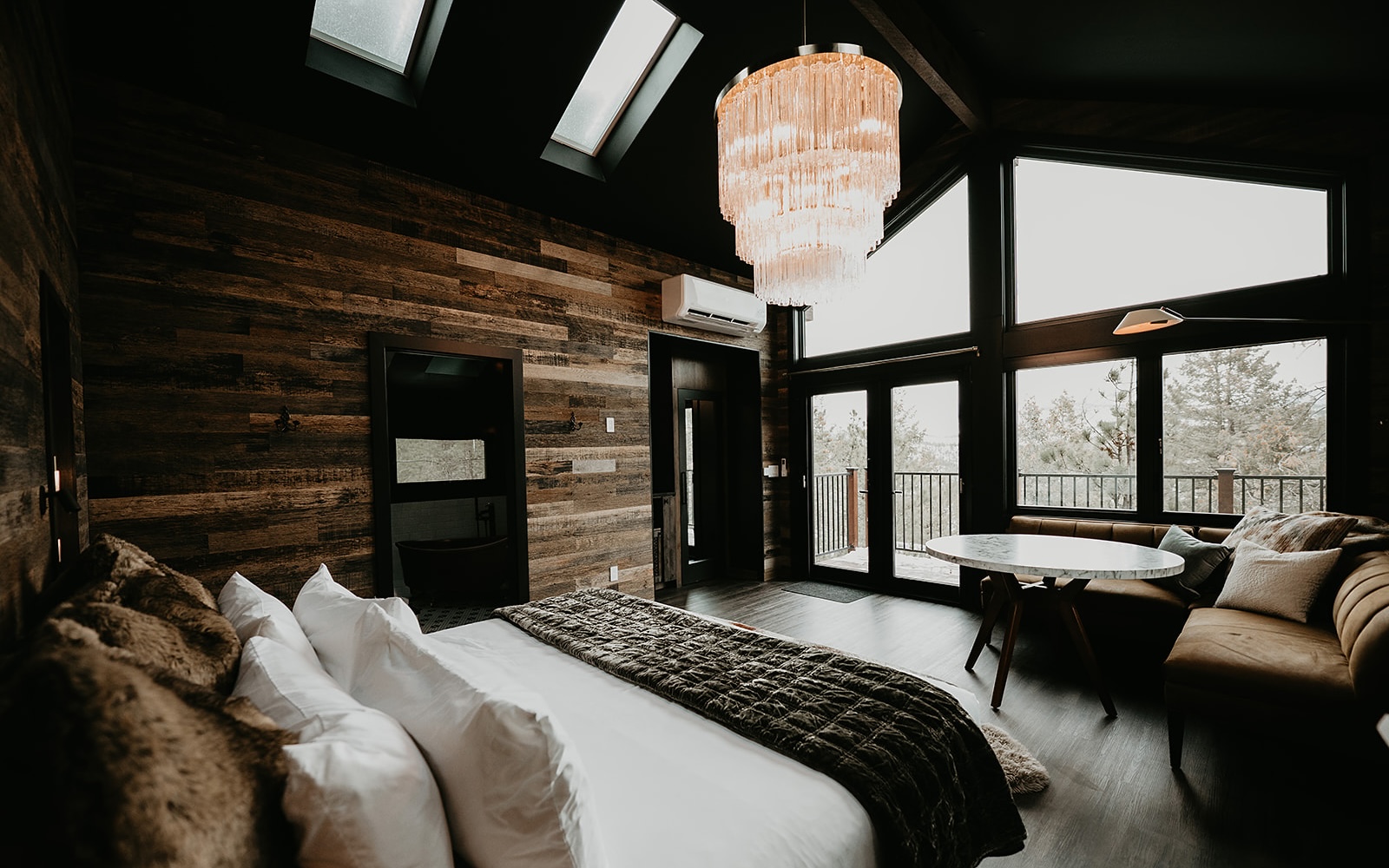 Large windows and a chandelier over a king bed
