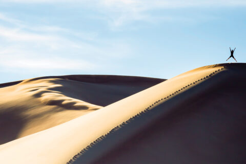 A person jumping on a sand dune