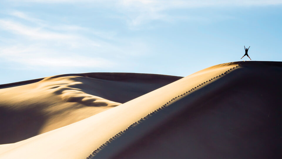 A person jumping on a sand dune