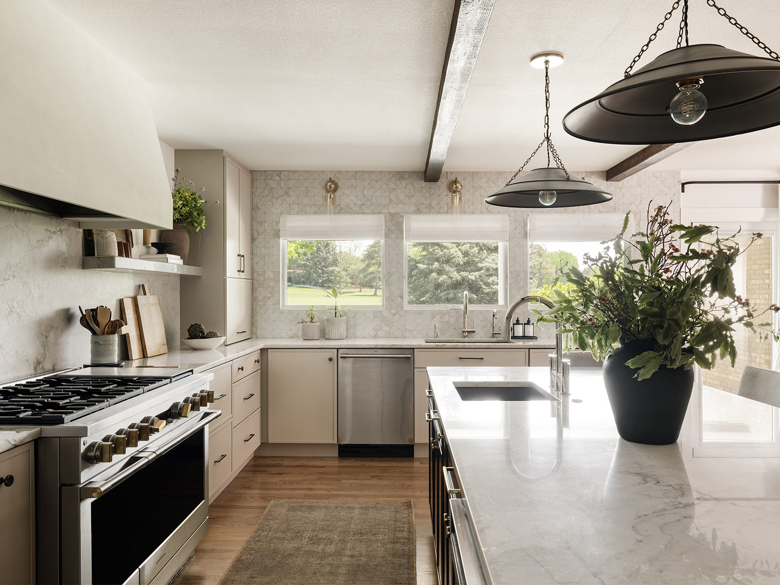 White, sunny kitchen with black light fixtures and three windows