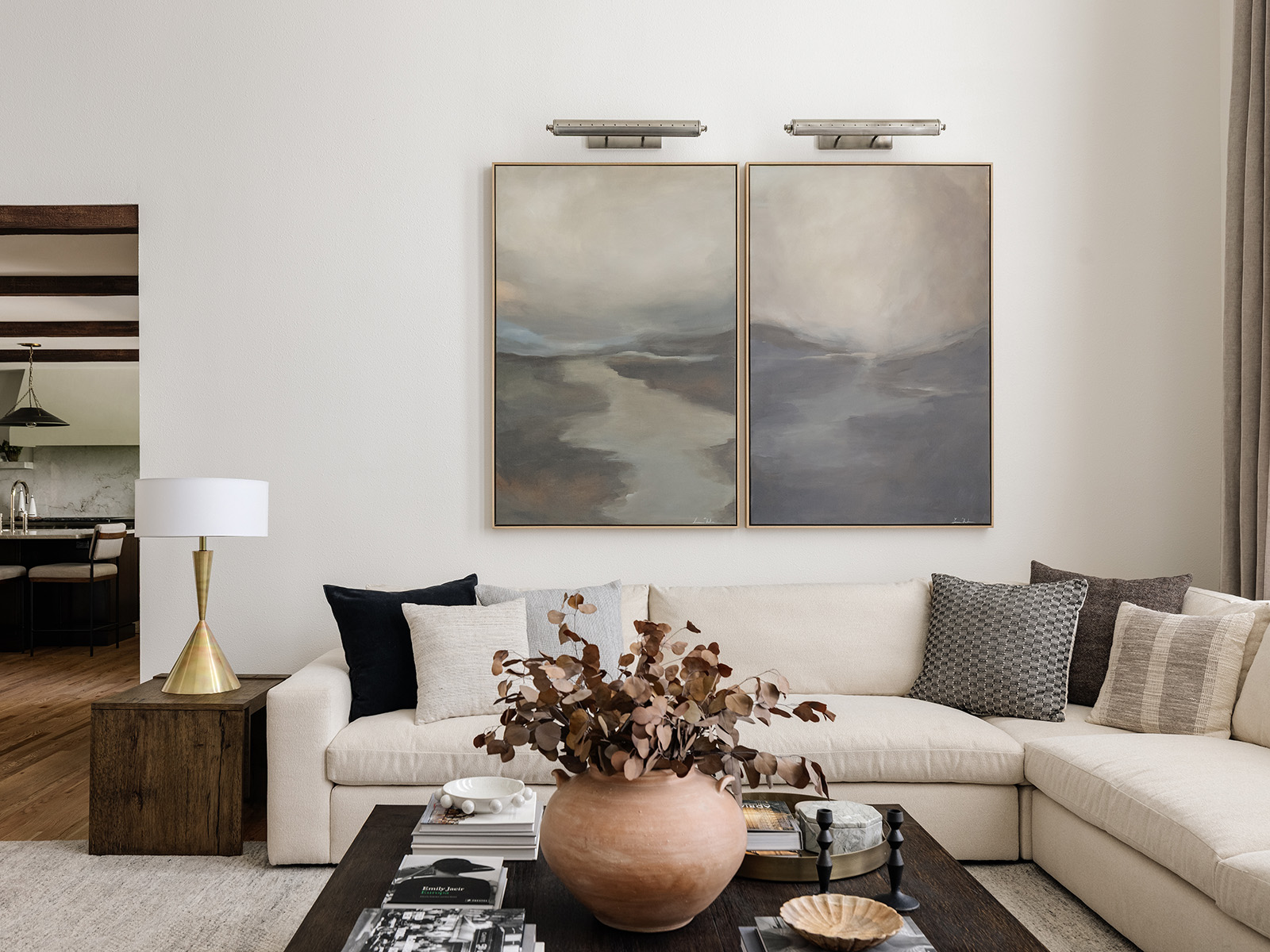 White L-shaped sofa with large landscape artwork on the wall behind it