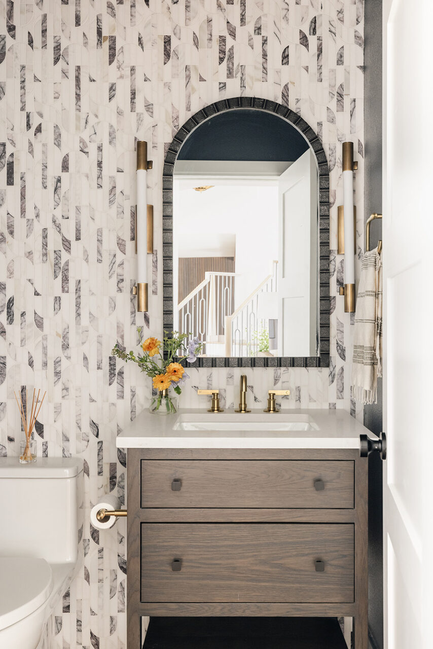 Bathroom with white wallpaper and an arched black mirror