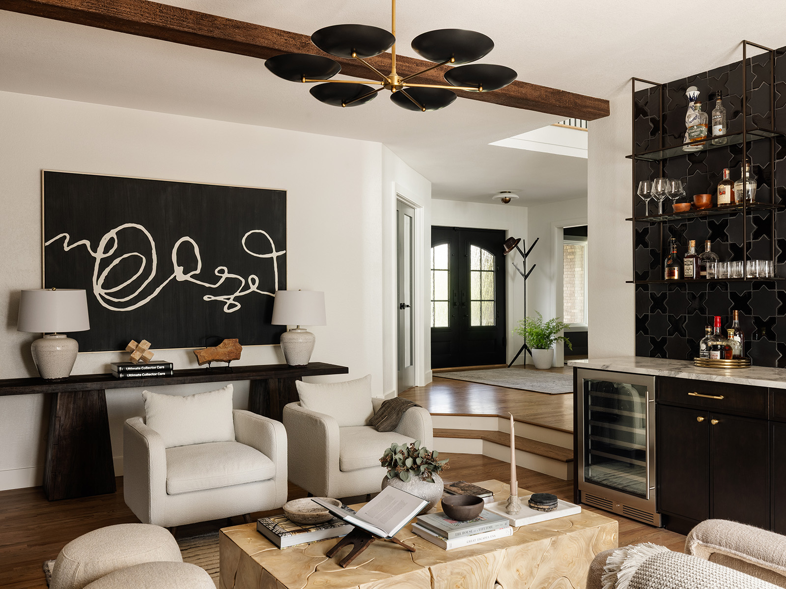 Modern lounge area with a black chandelier, white seating and a black bar