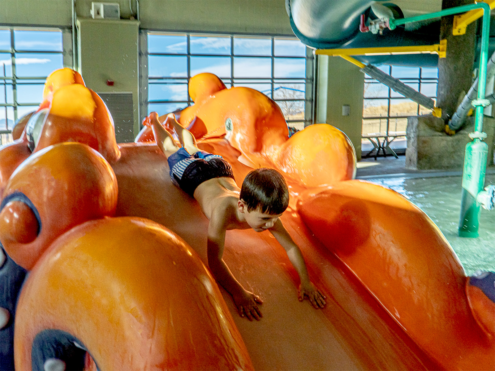 A kid going down an orange slide thing from Soft Play at the Paul Derda Recreation Center