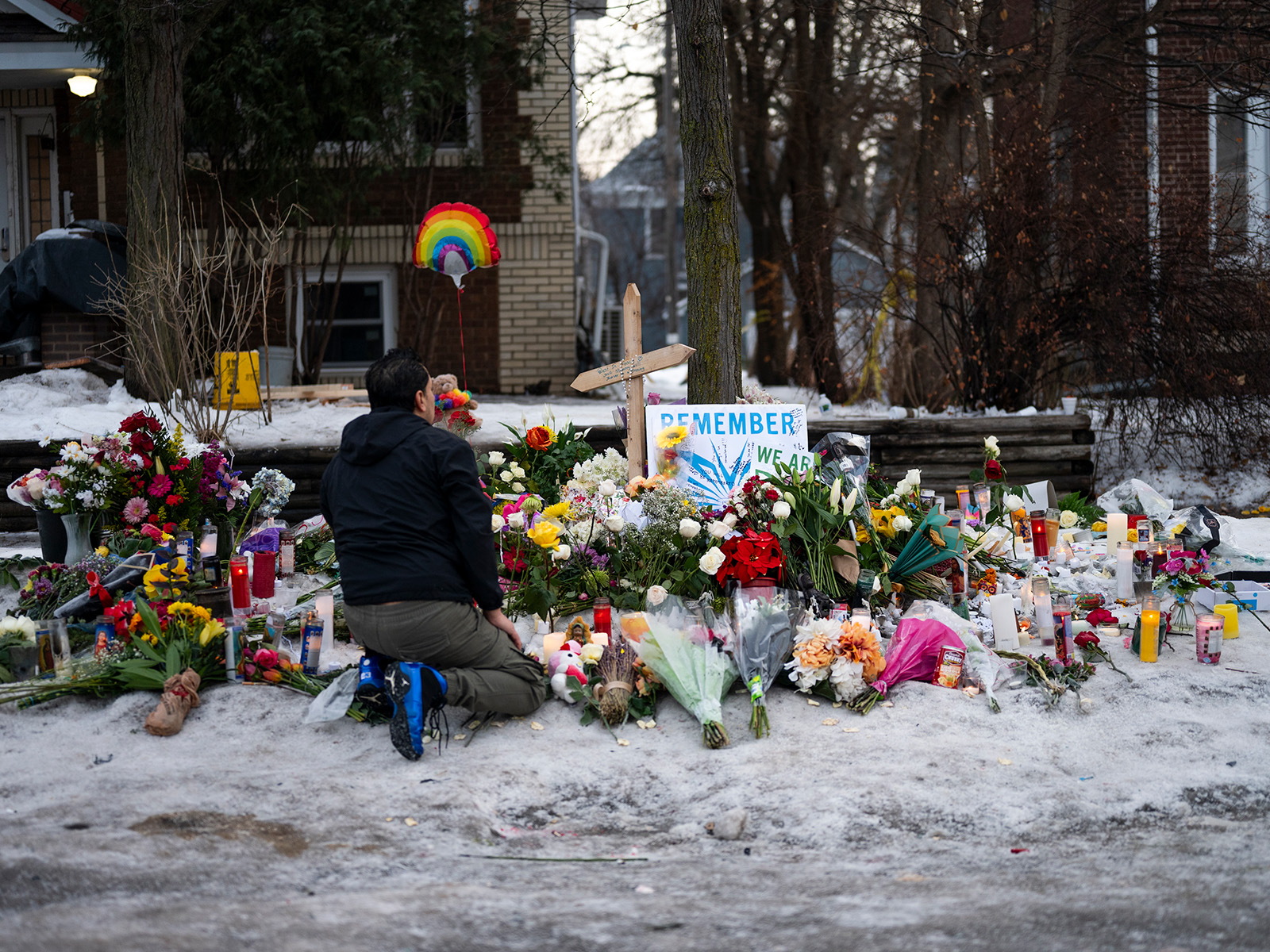 Man kneels at a memorial for Renee Good near the site of her shooting