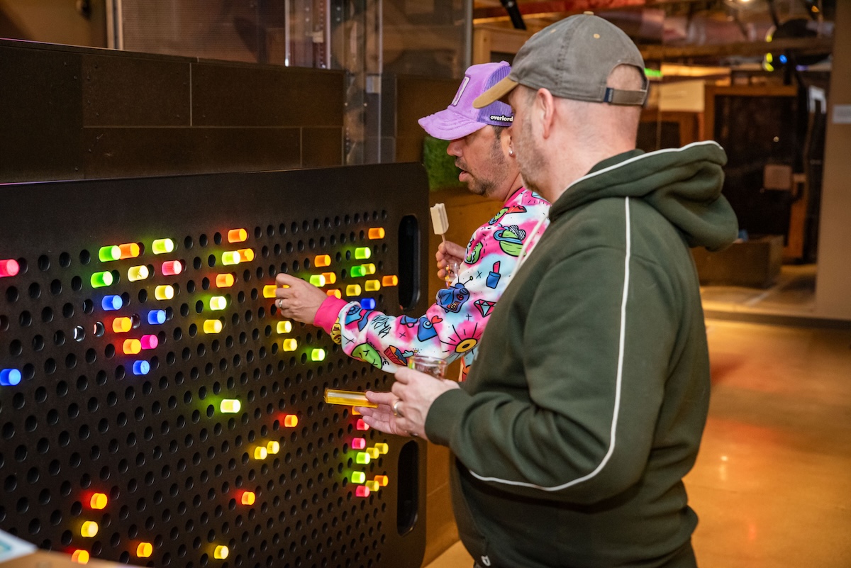 Two adult men play with a giant Lite Brite
