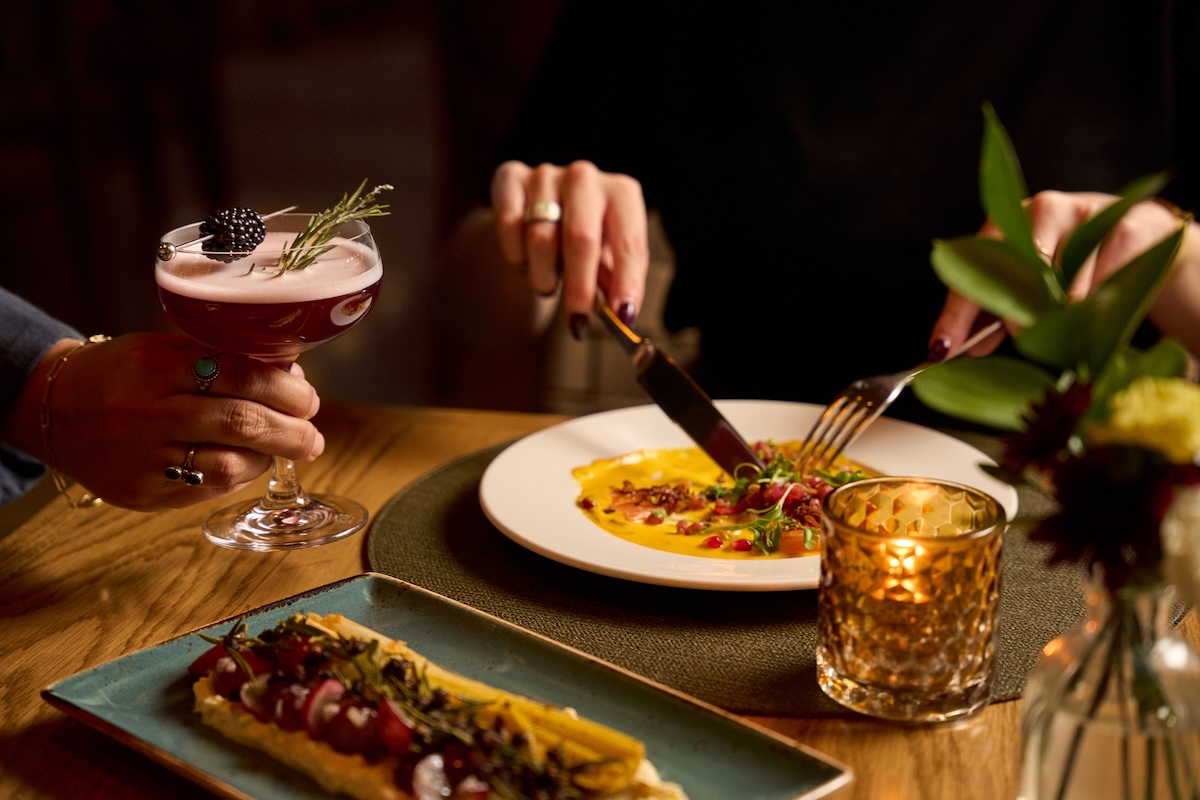 Dinner dishes and a pink cocktail garnished with rosemary