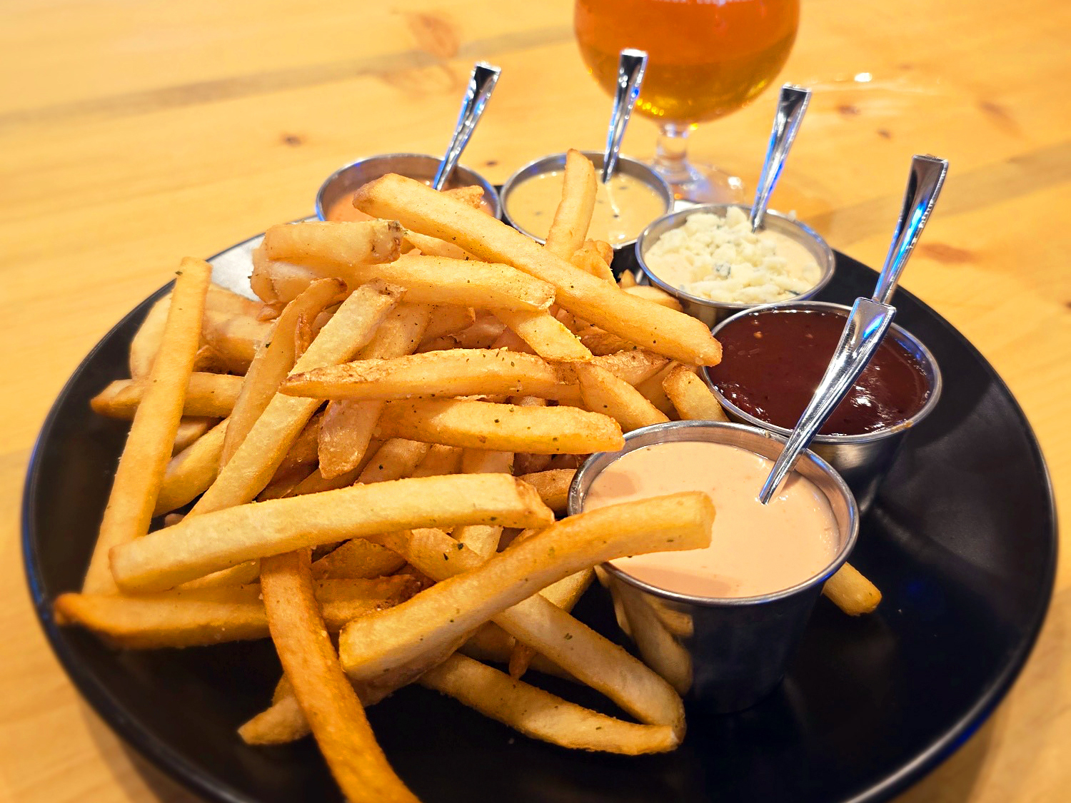 A plate of french fries with various dipping sauces