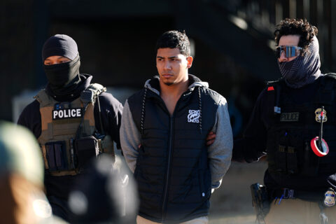 Law officials escort a man from an apartment to a waiting utility vehicle for transport during a raid Wednesday, Feb. 5, 2025, in east Denver