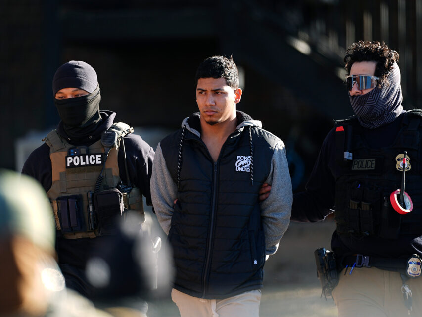 Law officials escort a man from an apartment to a waiting utility vehicle for transport during a raid Wednesday, Feb. 5, 2025, in east Denver