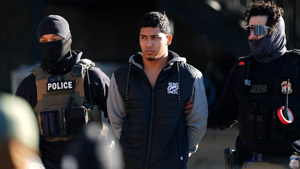 Law officials escort a man from an apartment to a waiting utility vehicle for transport during a raid Wednesday, Feb. 5, 2025, in east Denver