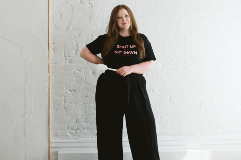 Shelby Boolay poses in a shirt that says "Shut Up and Sit Down"