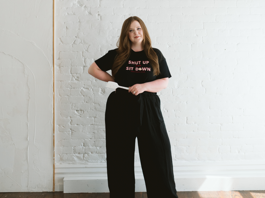 Shelby Boolay poses in a shirt that says "Shut Up and Sit Down"