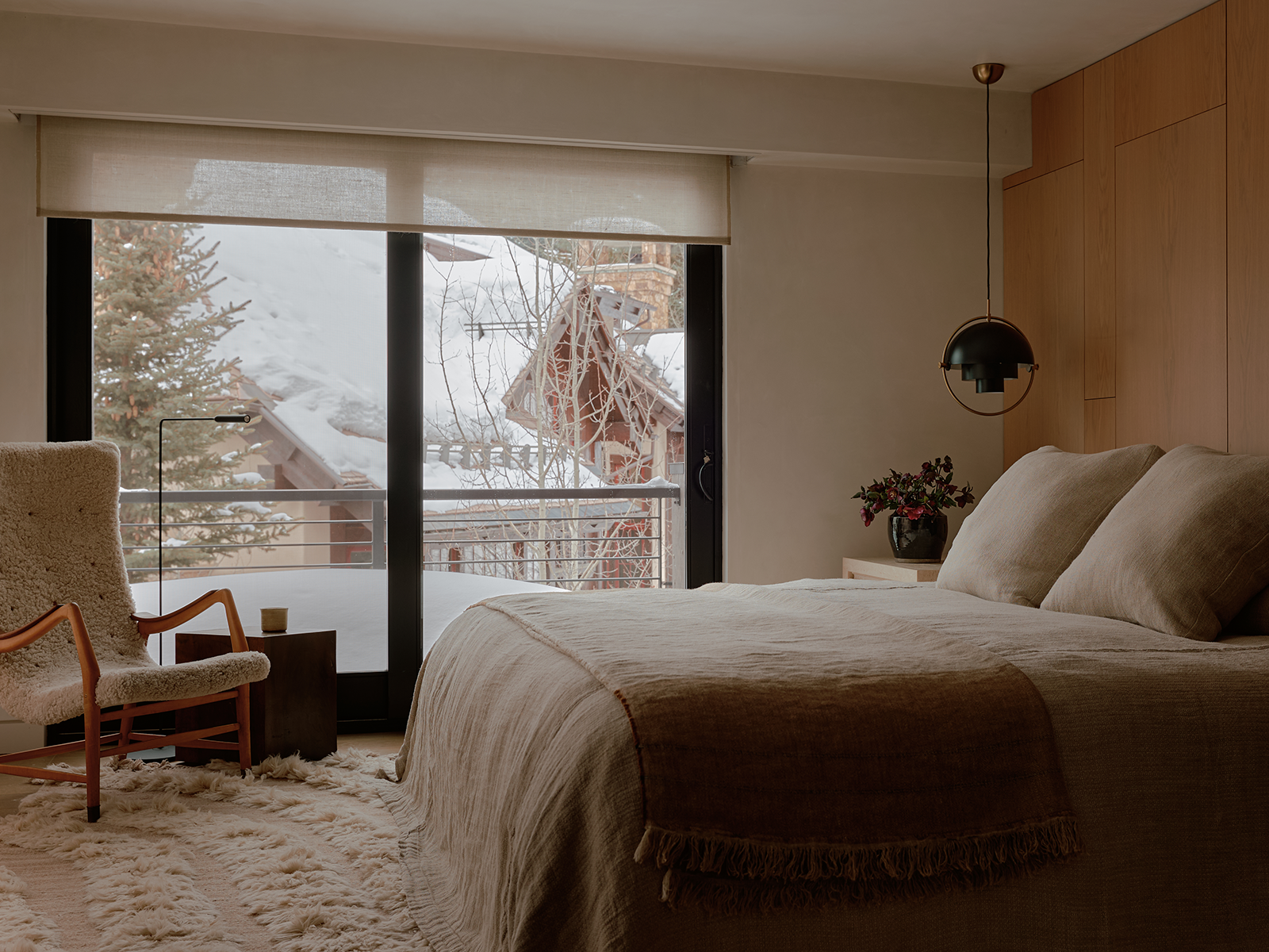 Bedroom with white linens, a sliding glass door, and a hanging light fixture beside the bed