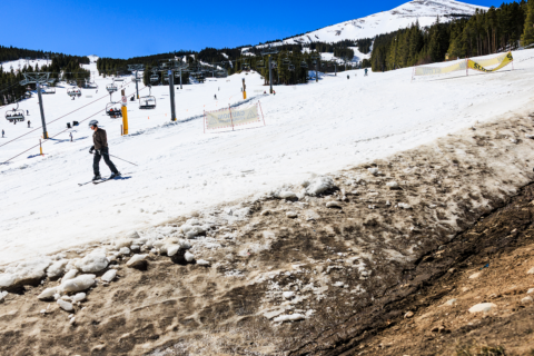People ski past an exposed hillside at Breckenridge Ski Resort as temperatures reach into the 50s on March 18, 2026.