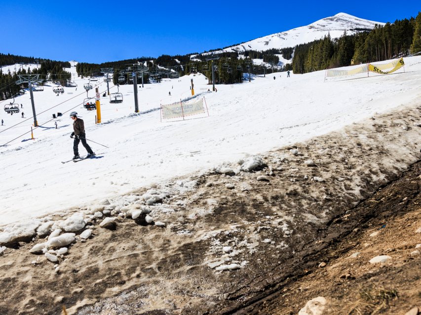 People ski past an exposed hillside at Breckenridge Ski Resort as temperatures reach into the 50s on March 18, 2026.