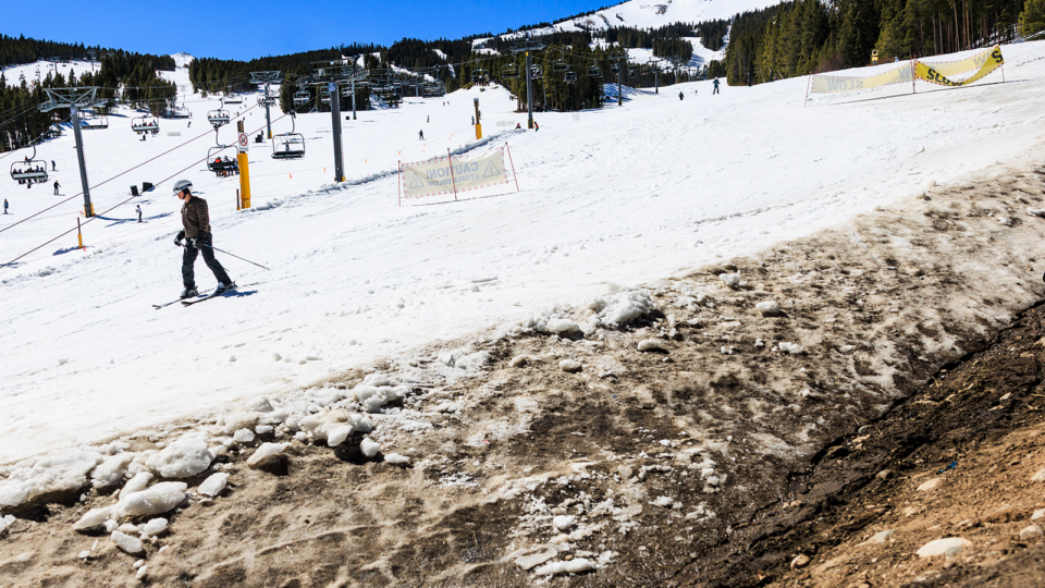 People ski past an exposed hillside at Breckenridge Ski Resort as temperatures reach into the 50s on March 18, 2026.