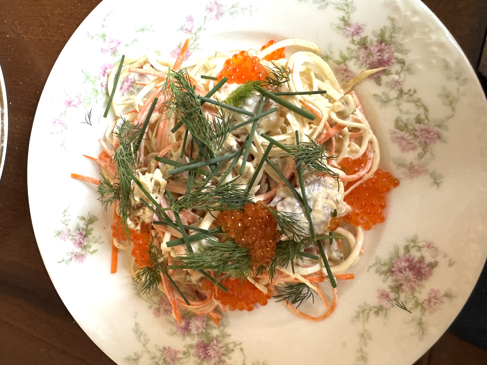 A flower-print china dish with celeriac salad, trout roe, and dill