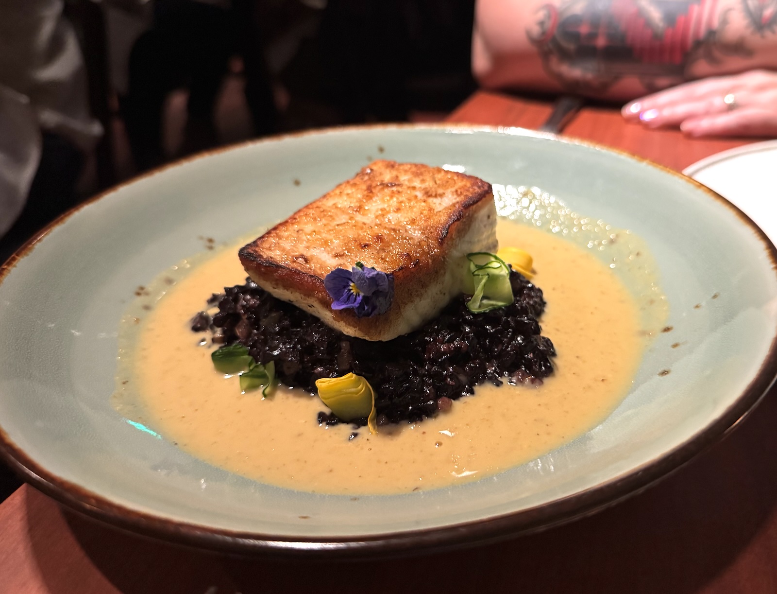 Pan-seared halibut on black rice with green curry sauce.