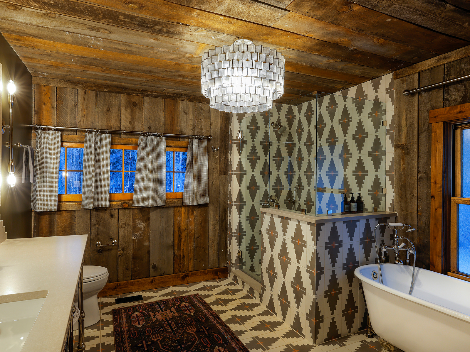 A bathroom with a patterned tile shower and a clawfoot tub