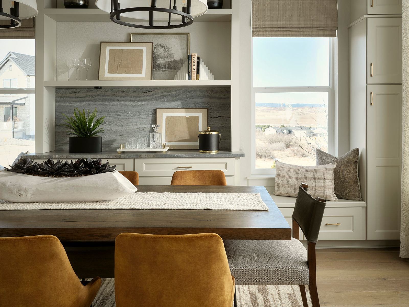Dining room table topped with succulents and large windows on the back wall