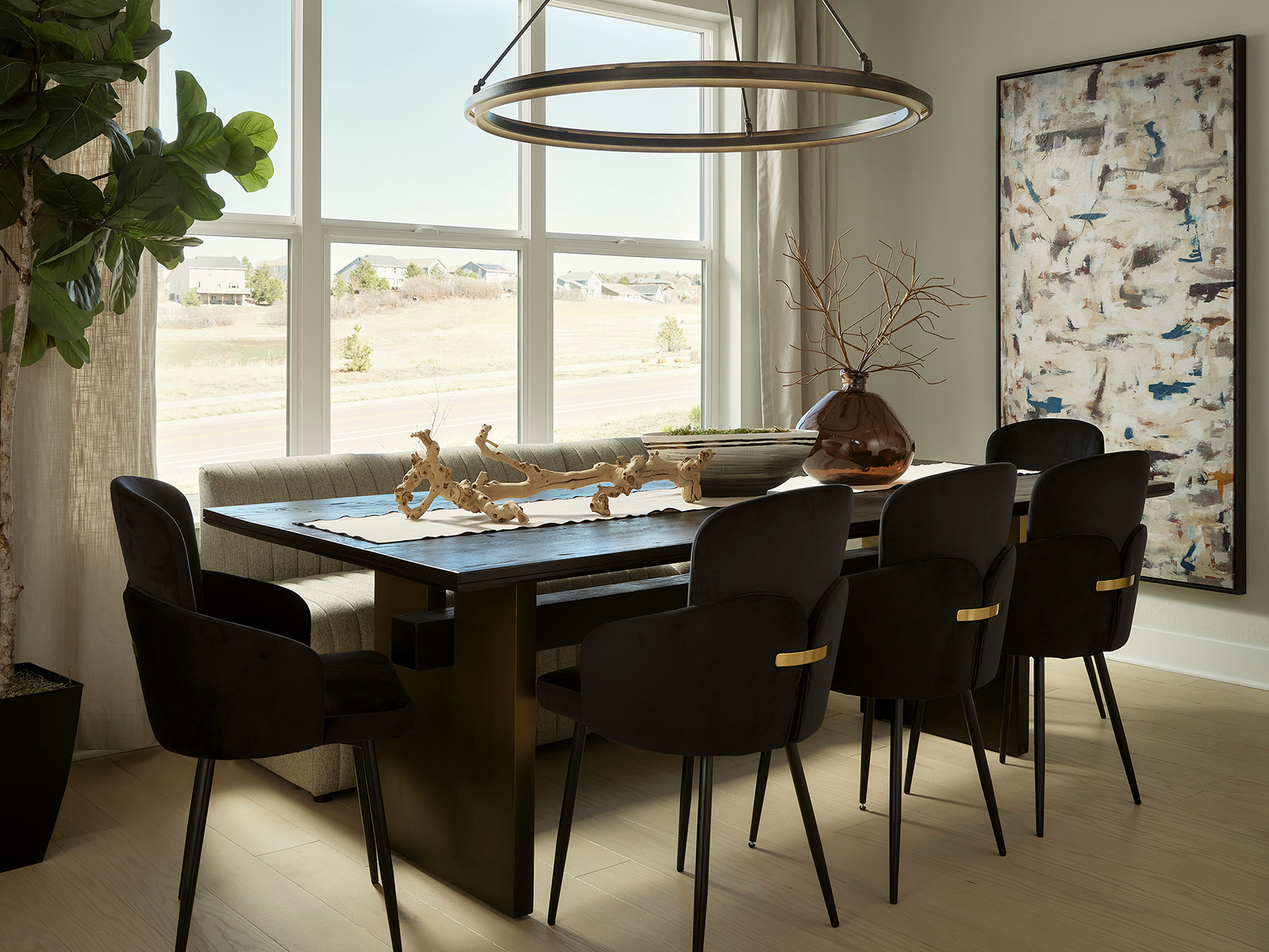 Dining table in a room with large windows and a big, circular chandelier overhead