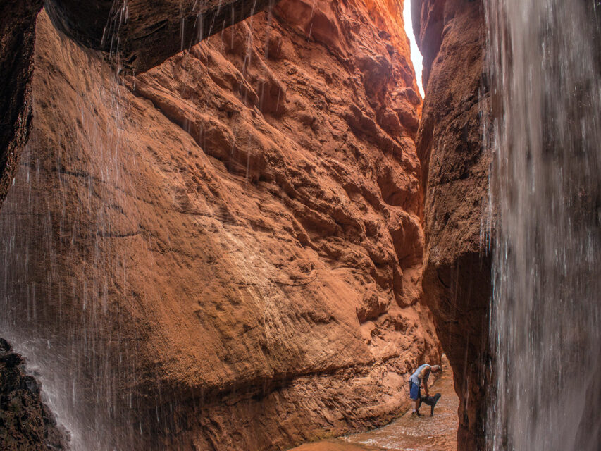 A hiker and his dog in Mary Jane Canyon in Moab, Utah