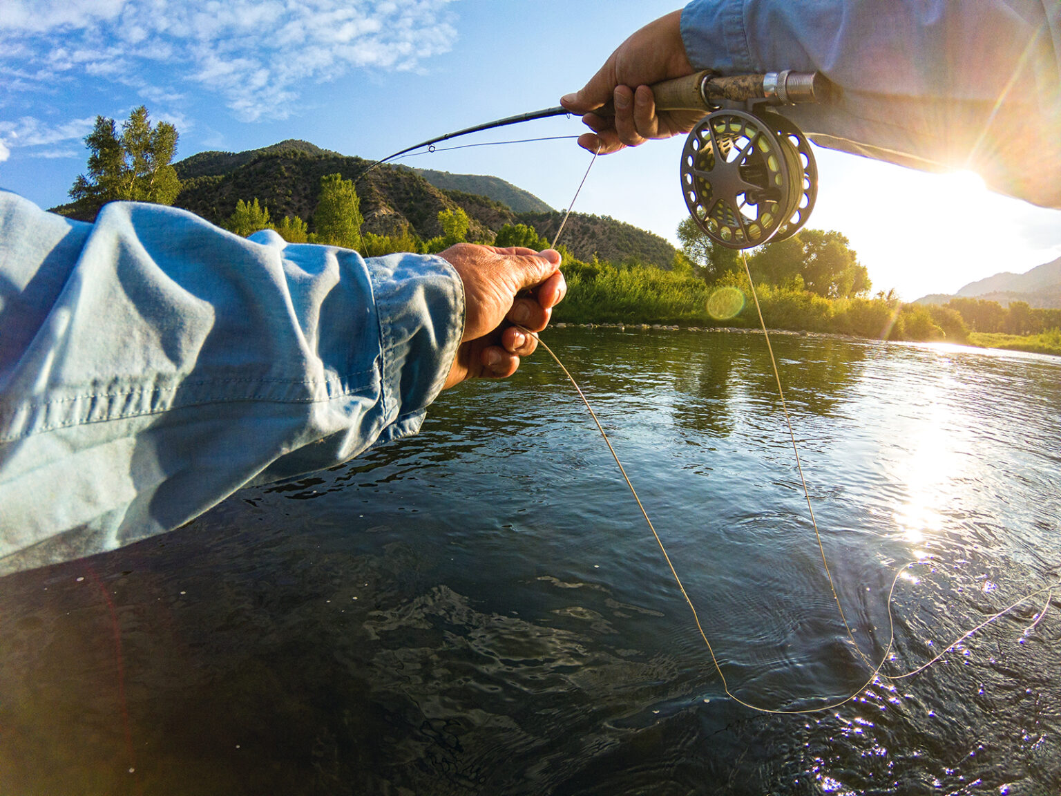 A POV shot of a man casting a fly-fishing line in a Colorado River