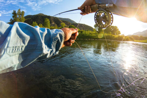 A POV shot of a man casting a fly-fishing line in a Colorado River