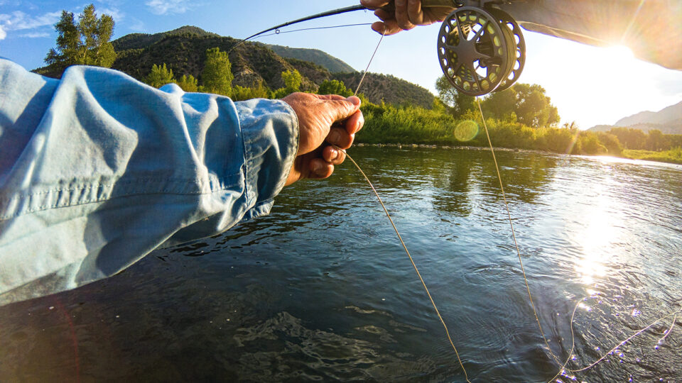 A POV shot of a man casting a fly-fishing line in a Colorado River