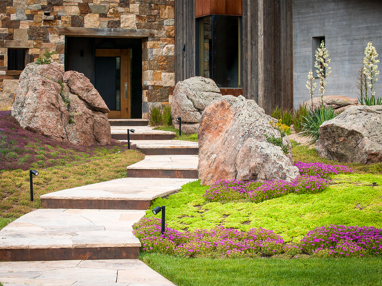 A path to a front door lined with boulders and plants