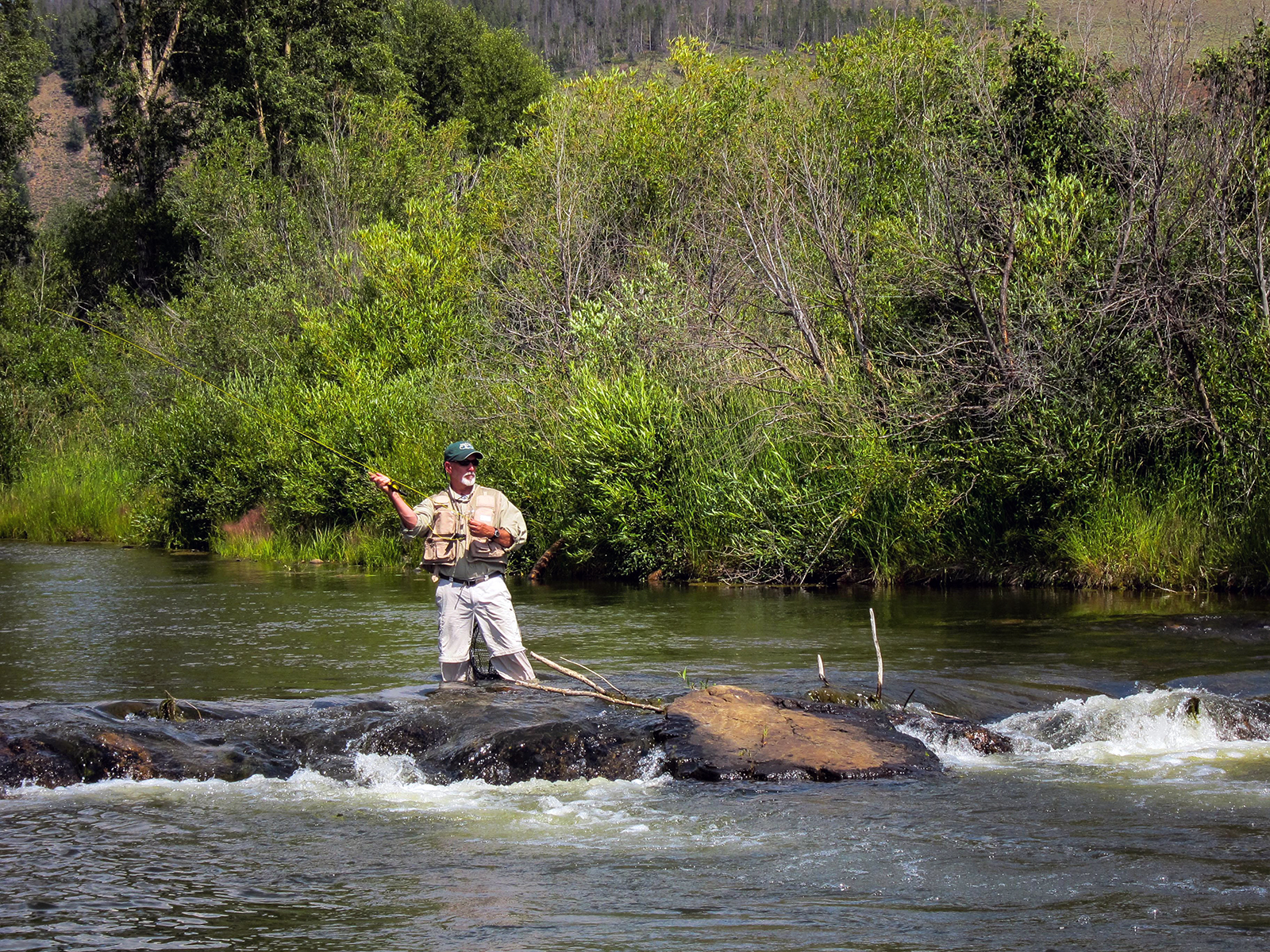 A man casting a fly-fishing line in a Colorado river