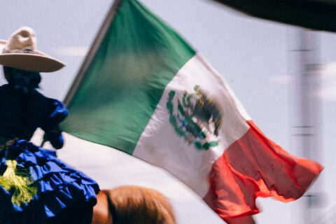 A charro handling a Mexican flag on horseback