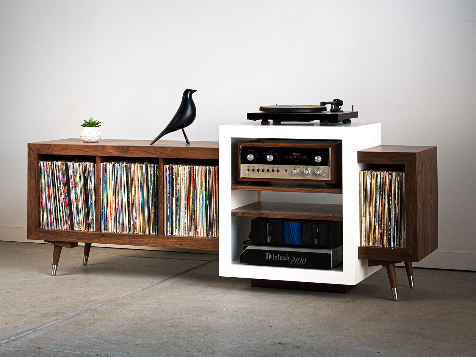 A record player on a plain wall with a bird statue