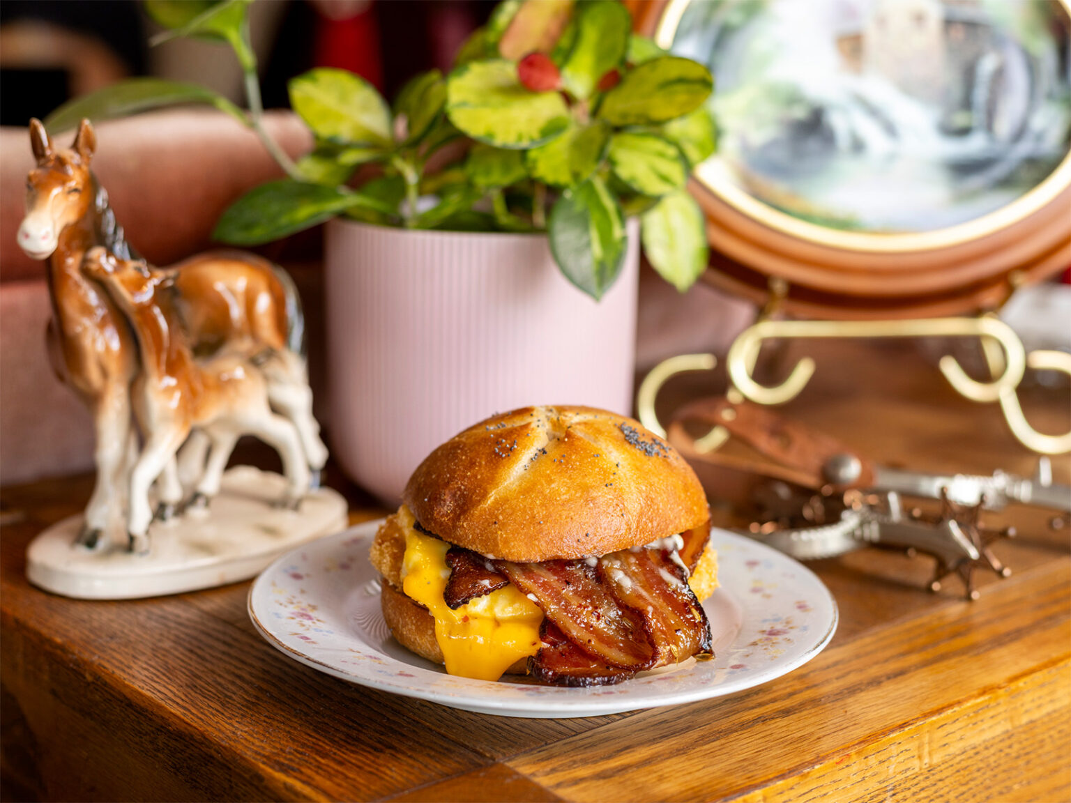 A breakfast sandwich on a plate with a houseplant