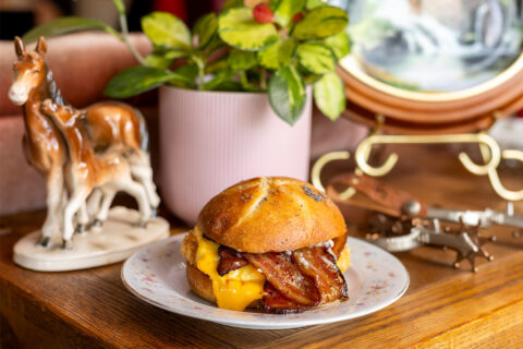 A breakfast sandwich on a plate with a houseplant