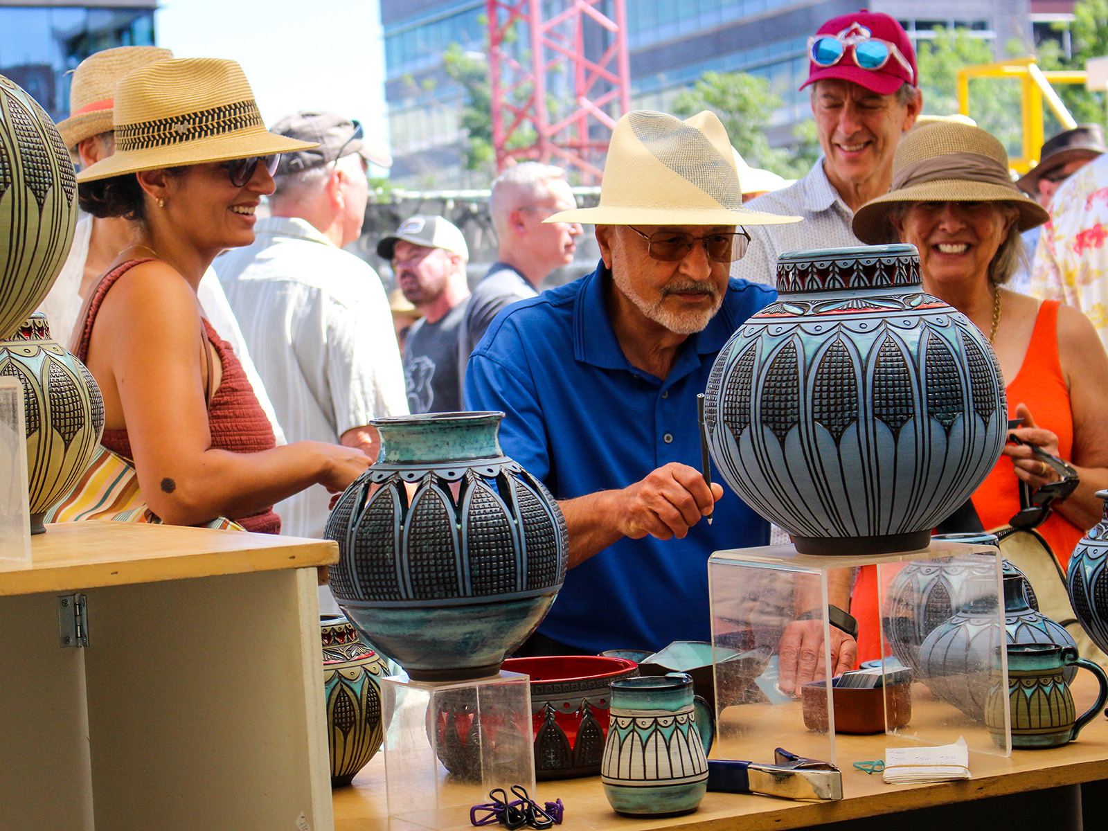 People admire a ceramics booth at an art festival