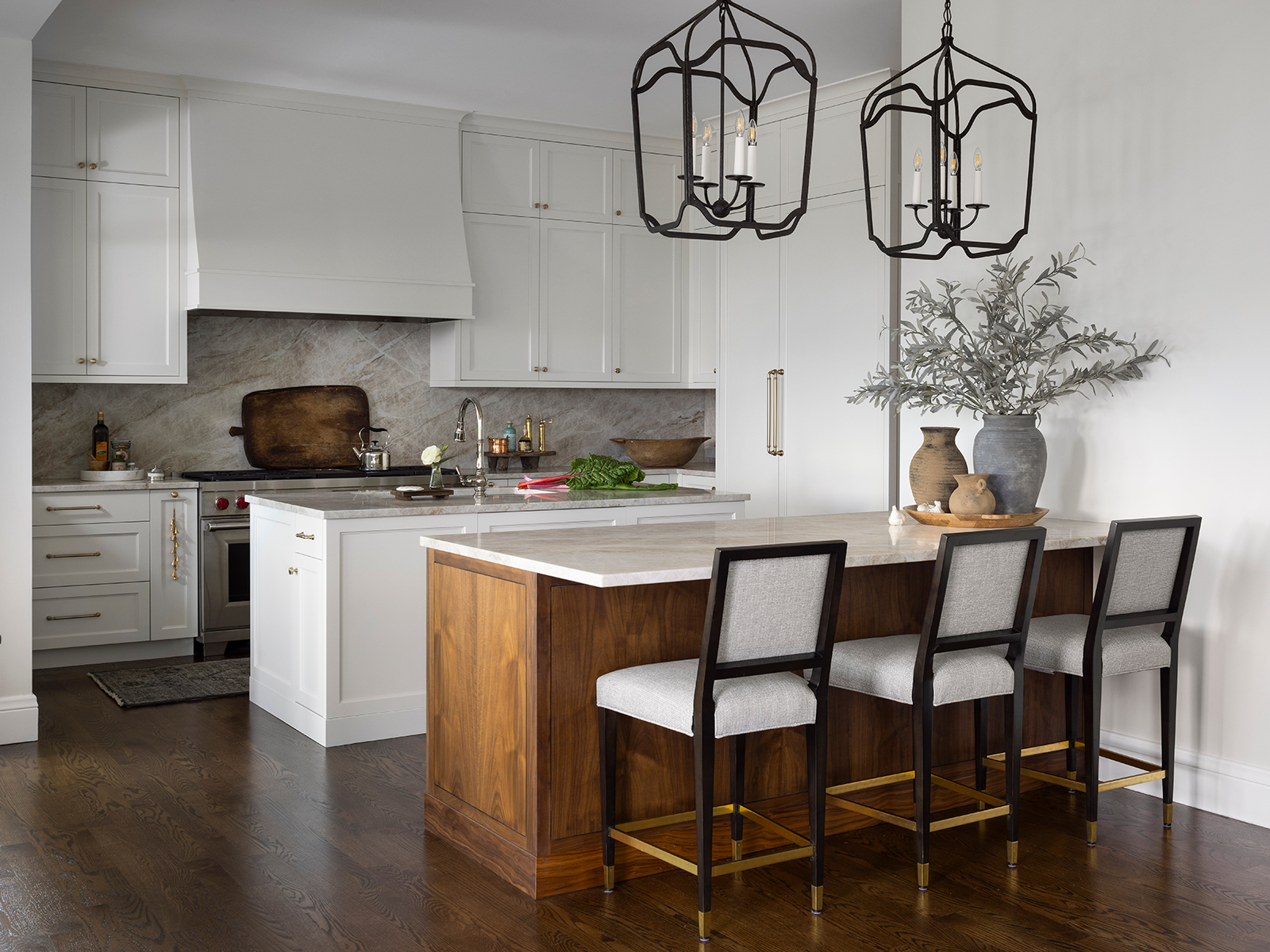 A white, modern kitchen with two slim islands and black pendant lighting