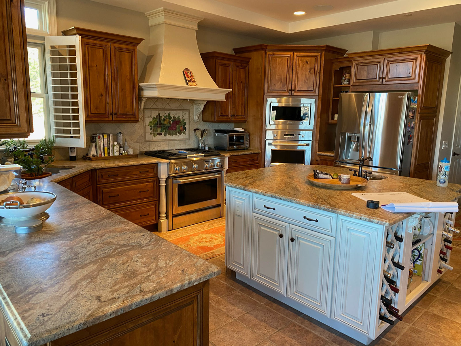 An outdated kitchen with upper wood cabinetry, lower white cabinetry and a large island