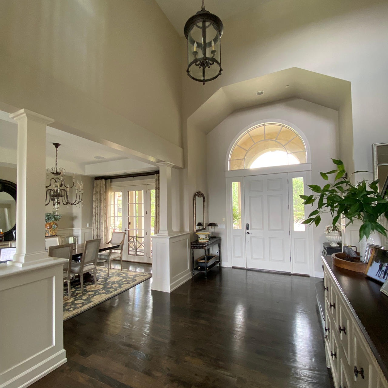 Beige two-story entryway with a small hanging chandelier