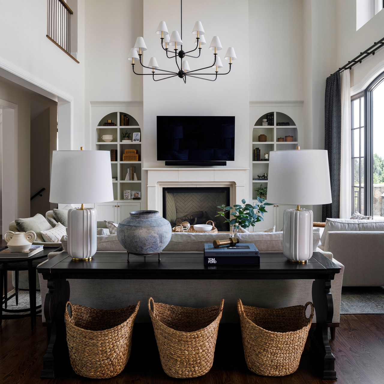Living room with an all-white, two-story fireplace and dark furniture