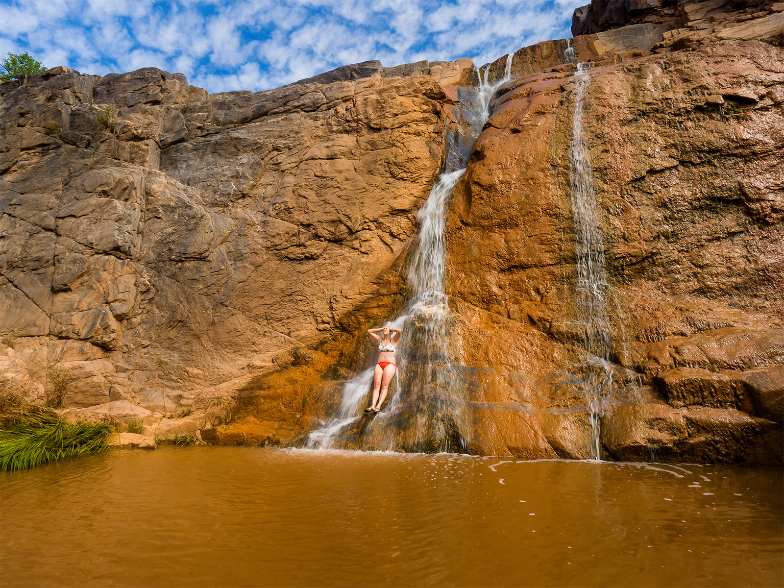 A female hiker rinsing off in a natural waterfall in Big Dominguez Canyon along the Big D-Little D Loop in Colorado