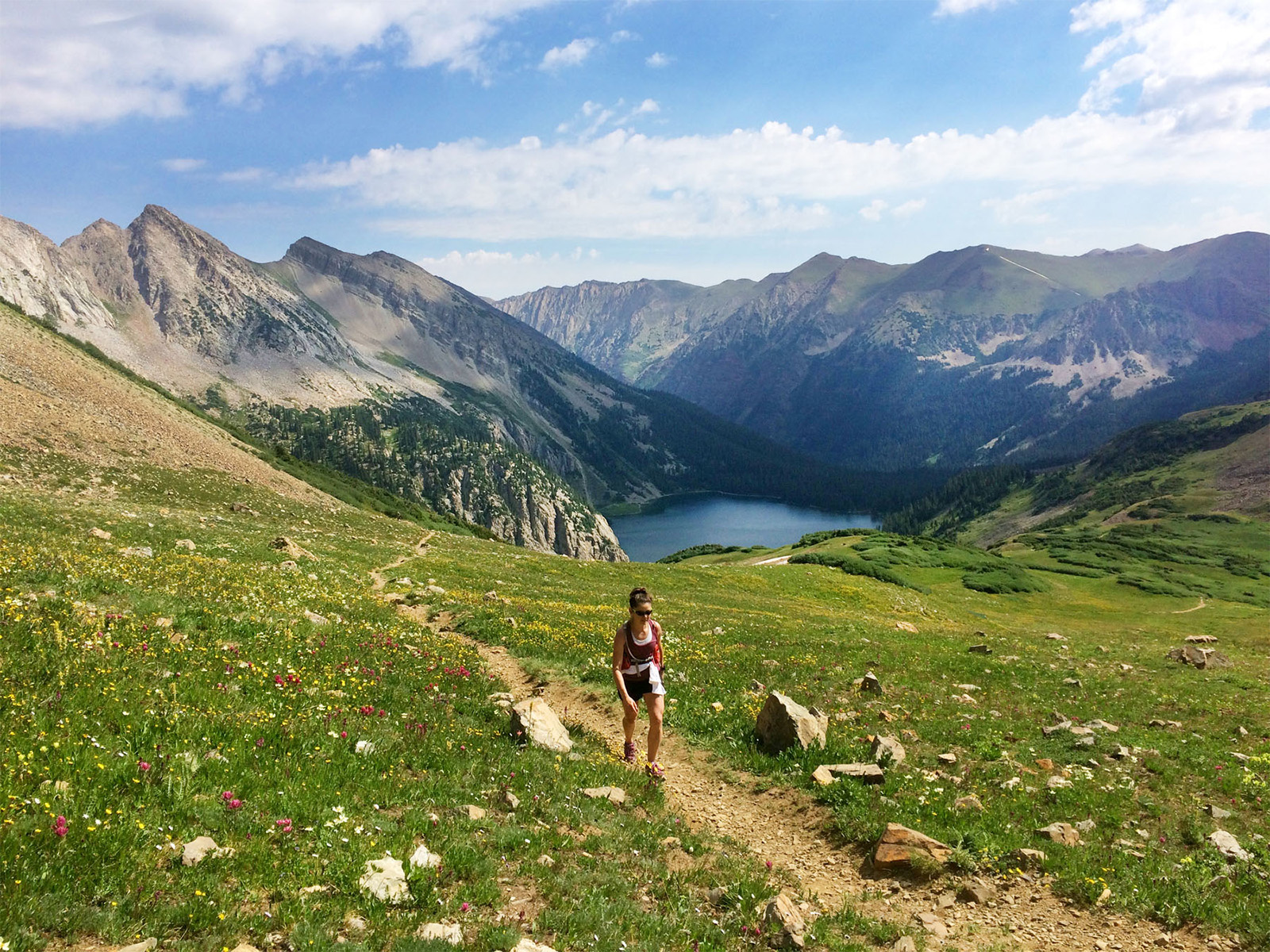 A hiker climbing through a verdant meadow on the flank of Snowmass Mountain in Colorado