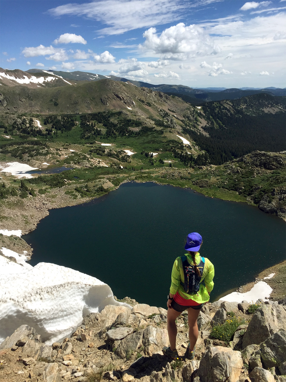 A trail runner peers over King Lake along the High Lonesome Loop in the Indian Peaks Wilderness in Colorado