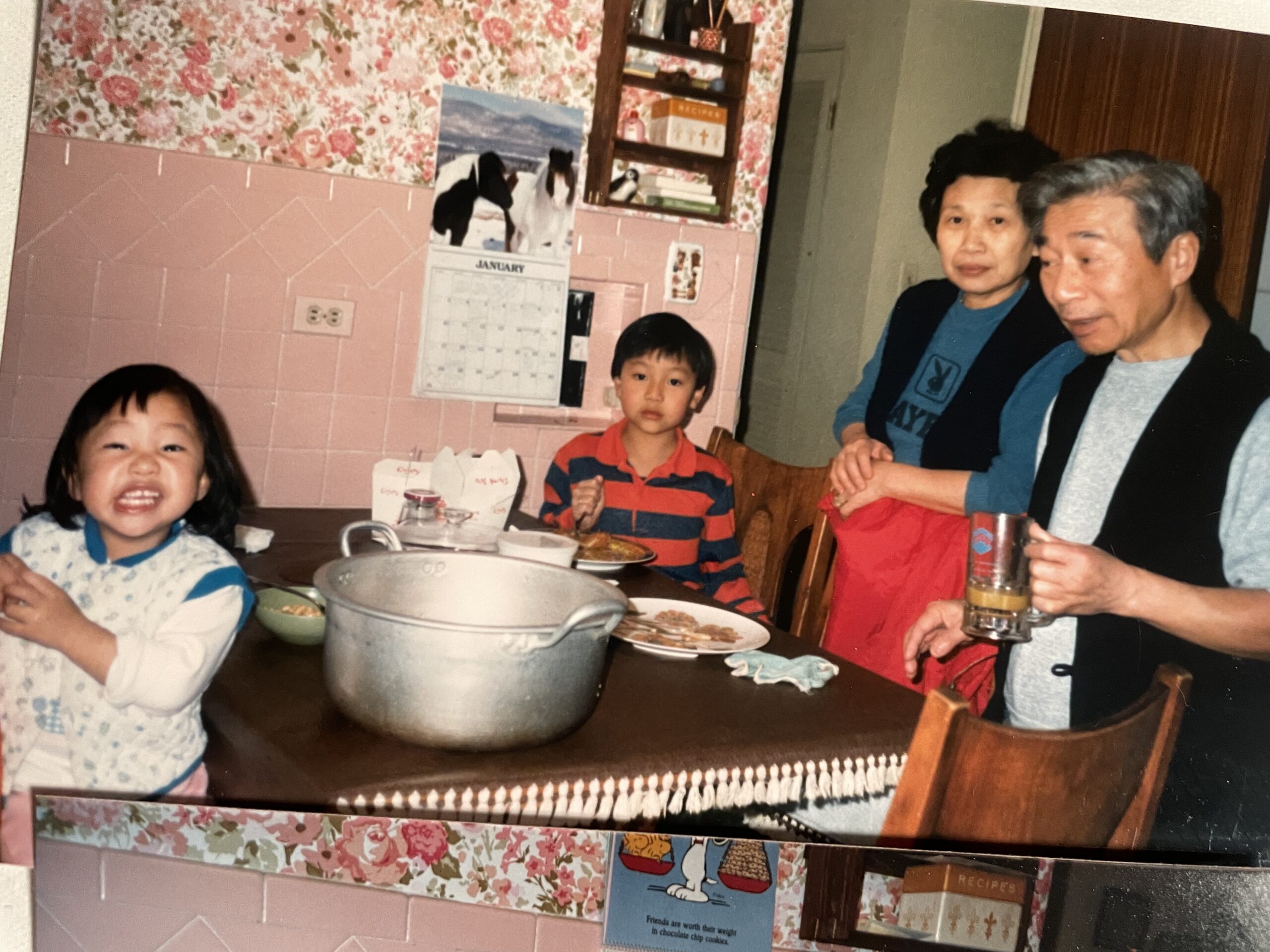 Parents and two children father around a table in a pink kitchen