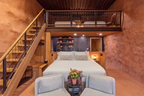 A bed, chairs, and staircase in a hotel room at Honey Rock Landing in Delta County